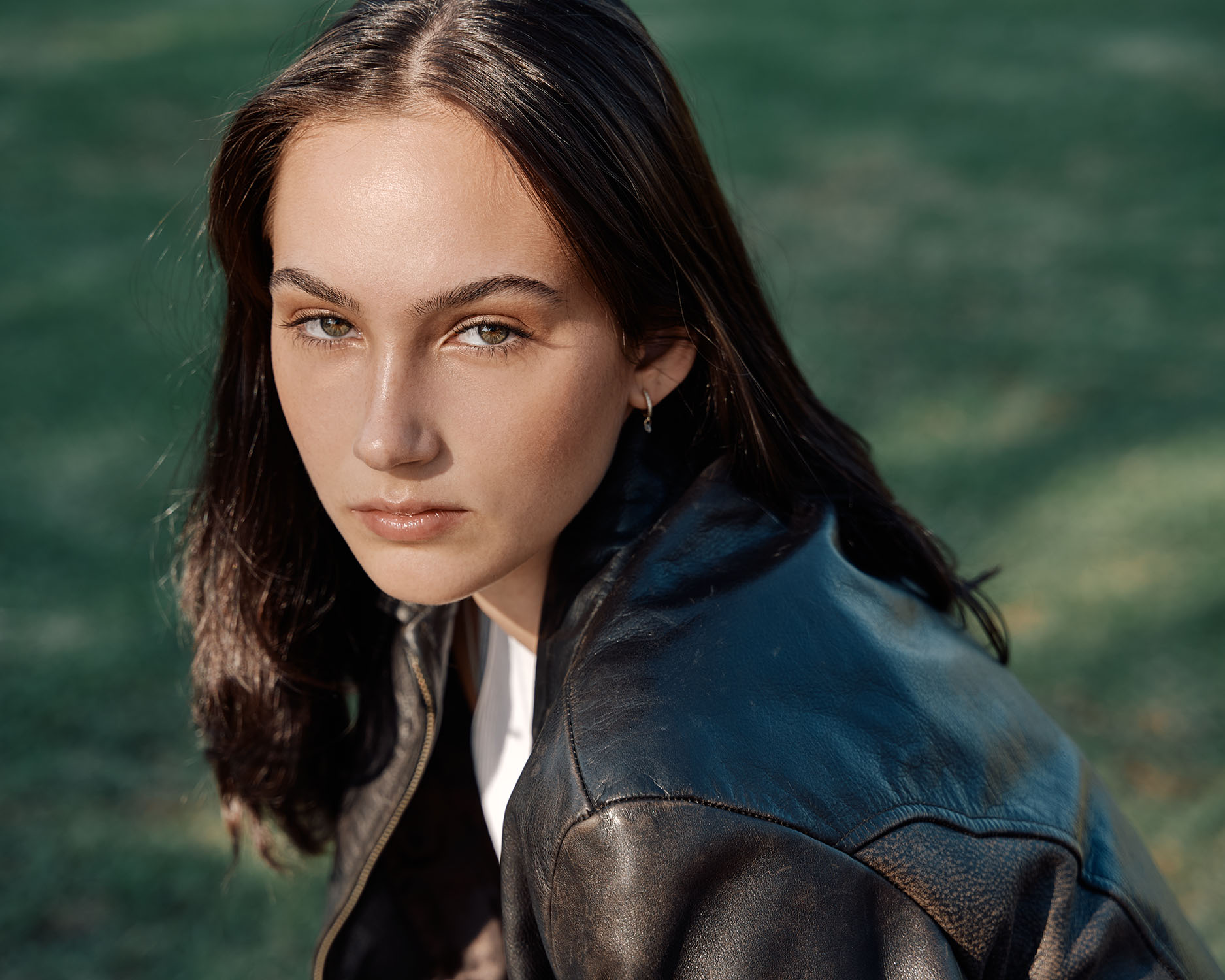 Environmental portrait of a young woman in a leather jacket on a grass background in San Diego — Headshots by Guffy, San Diego