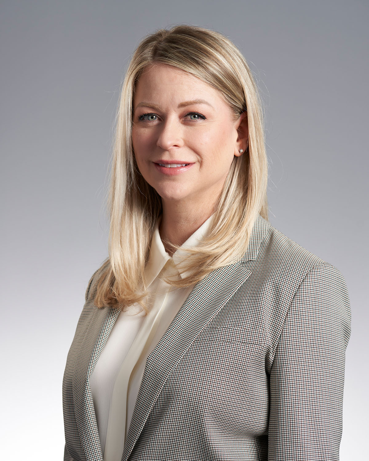 Professional corporate headshot of a woman in a houndstooth blazer against a gray gradient background — Headshots by Guffy, San Diego